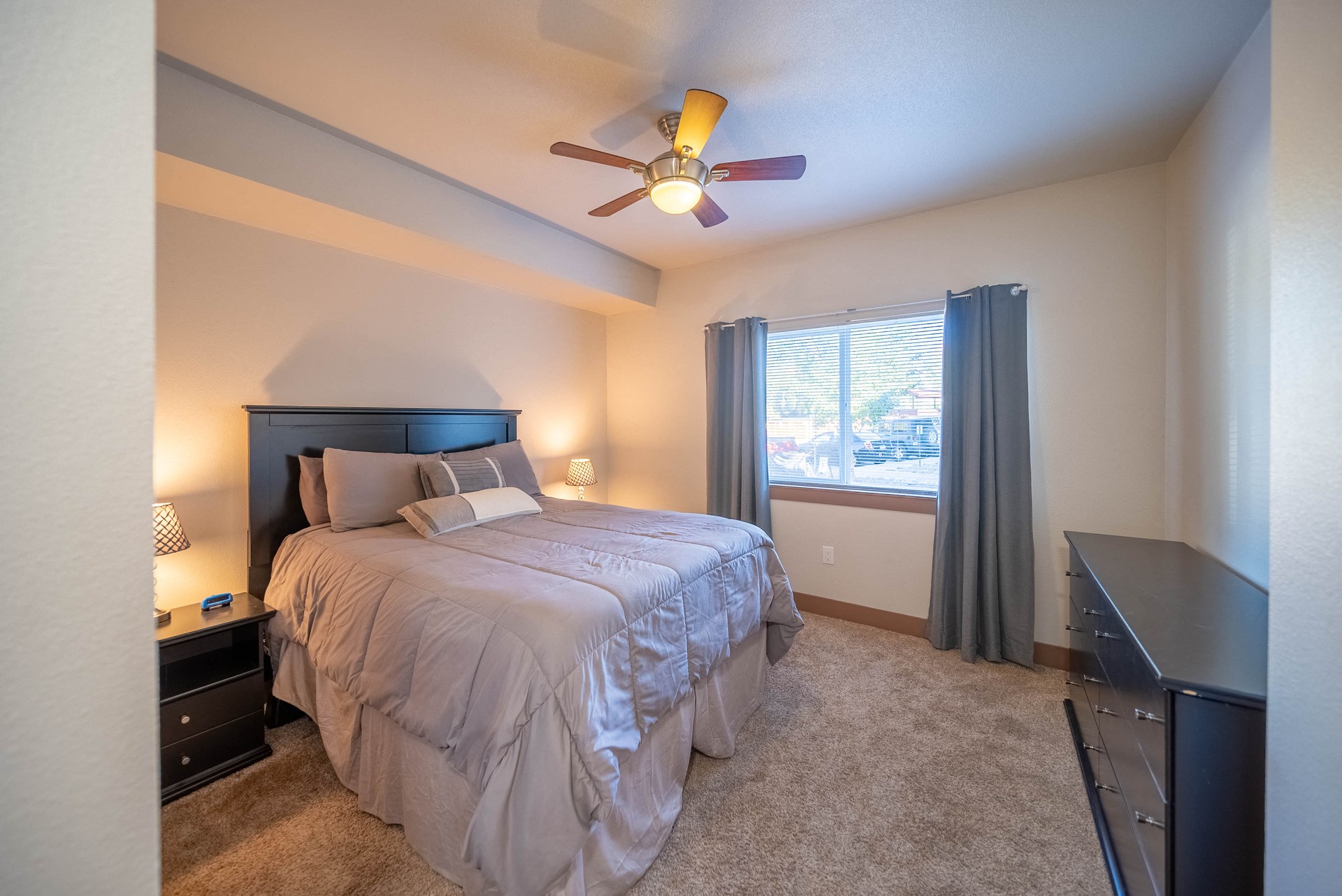A bedroom with a bed, nightstand, and window.